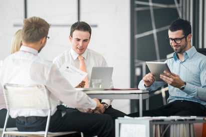 A group of corporate people discussing facility management software by an office table